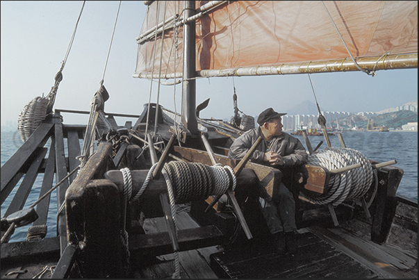 On board of the history Duk Ling junk boat and on the horizon, the skyscrapers of Kowloon