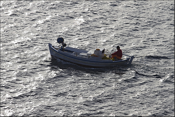 Fisherman returns in the evening in the port of Pollonia on a typical boat of the island Fisherman returns in the evening in the port of Pollonia on a typical boat of the island