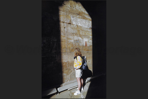 City of Edfu. Horus Temple. Interior of the temple. Interest of a tourist in front of the hieroglyphs