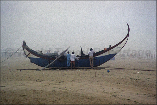 In the morning mists the ancient silhouettes of fishing boats appear on the beach In the morning mists the ancient silhouettes of fishing boats appear on the beach