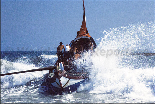 The boat is at the mercy of the big waves breaking on the beach