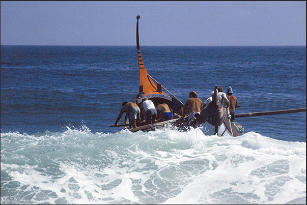 With great effort the boat overcomes the front of the waves breaking on the beach