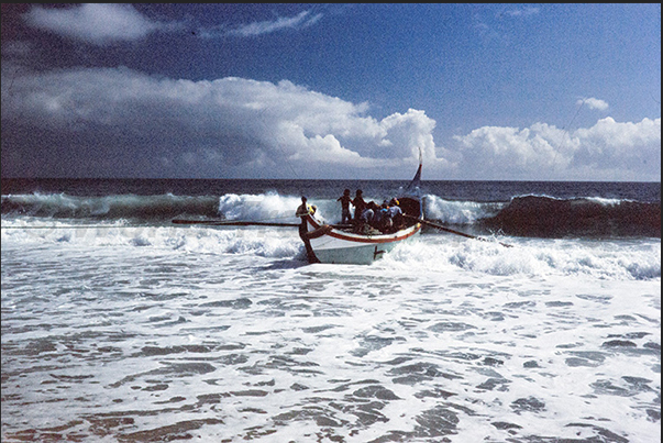 The boat with the fishermen takes advantage of the swell to reach the shore The boat with the fishermen takes advantage of the swell to reach the shore