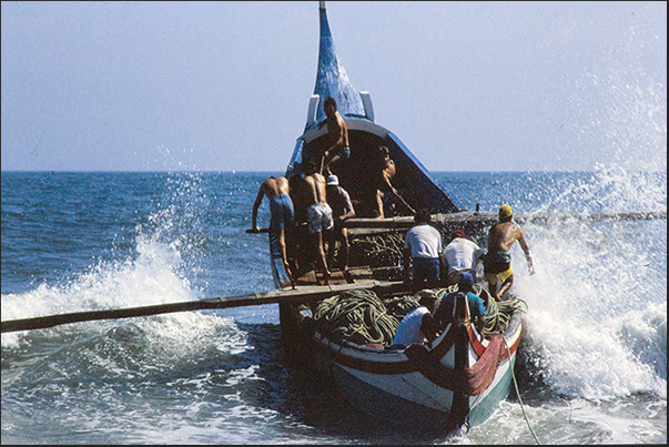 The boat is at the mercy of the big waves breaking on the beach