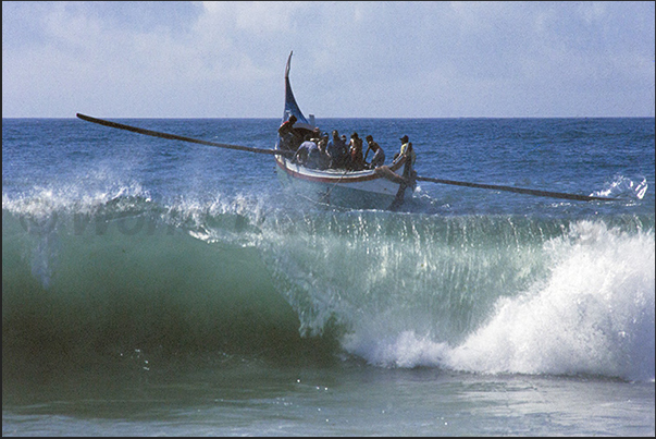 With great effort the boat overcomes the front of the waves breaking on the beach