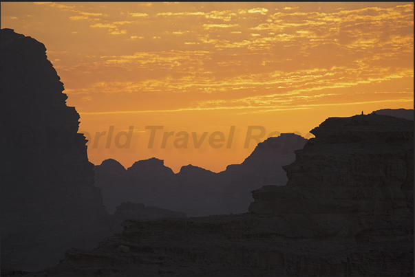 The sky lights up with colors, while the desert, plunged in darkness