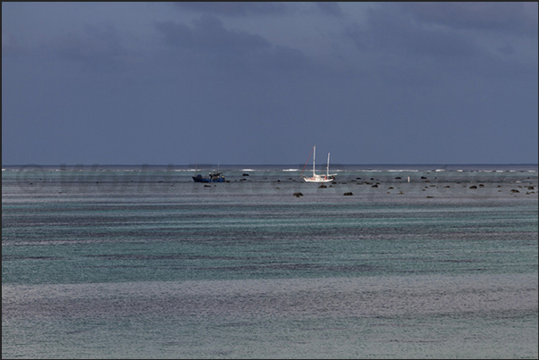 The sailing boat enter in the pass obtained by blasting with explosives the reef to create an access road to the Arutanga port