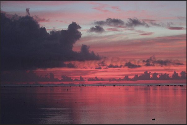 Sunset over the Pacific Ocean while the red sky is reflected on the calm waters of the lagoon Sunset over the Pacific Ocean while the red sky is reflected on the calm waters of the lagoon