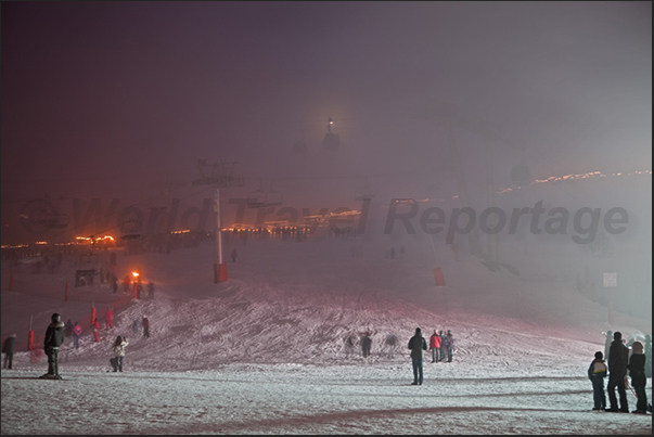 Festive evening on the Croisette in Les Menuires. The torchlight procession of teachers and students in the fog