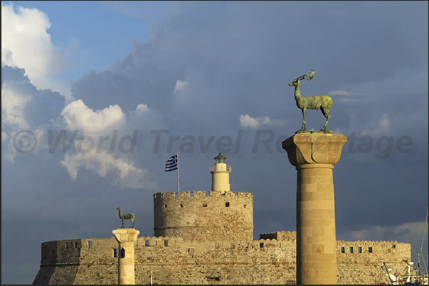 Lighthouse of fort St. Nicholas, (Mandraki Port) and columns with deer that, according to legend, freed the island from snakes Lighthouse of fort St. Nicholas, (Mandraki Port) and columns with deer that, according to legend, freed the island from snakes