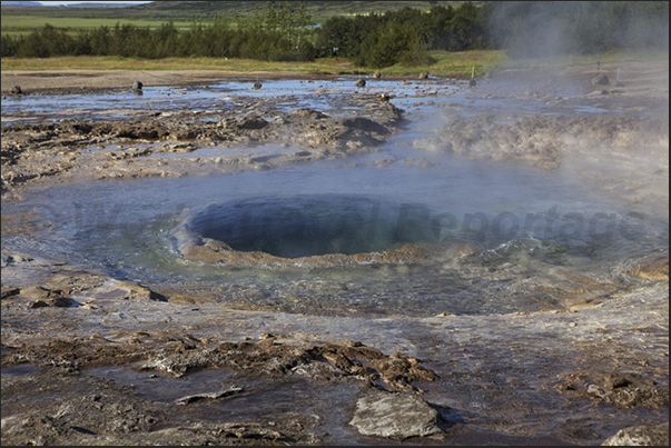 Selfoss, Park of Geyser. The geyser full of water, is going to explode Selfoss, Park of Geyser. The geyser full of water, is going to explode