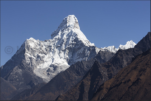 The tip of Mount Ama Dablam (6814 m) rises above the valley of the river Imja Kola The tip of Mount Ama Dablam (6814 m) rises above the valley of the river Imja Kola