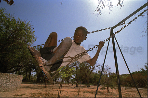 A child while playing on the swing under the hot afternoon sun