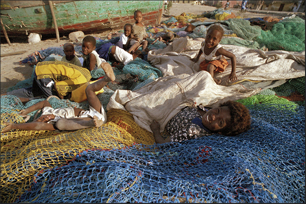 A group of children play on the beach, on a pile of fishing nets A group of children play on the beach, on a pile of fishing nets