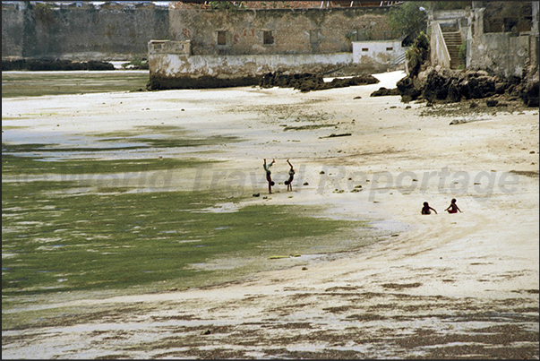 Some children play on the beach at low tide under the ramparts of San Sebastian Fortress. Some children play on the beach at low tide under the ramparts of San Sebastian Fortress.