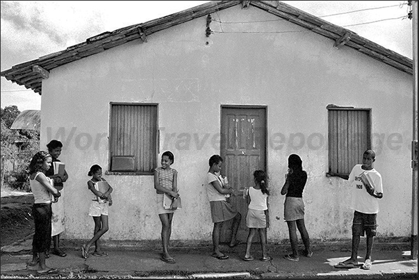 Boys and girls waiting the teacher in front of the small school of the farm Boys and girls waiting the teacher in front of the small school of the farm