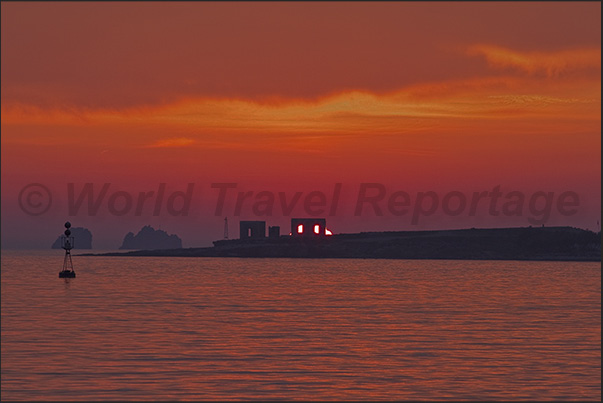 The sun sets between the ancient walls of Agios Fokas, the cape at the entrance to the port