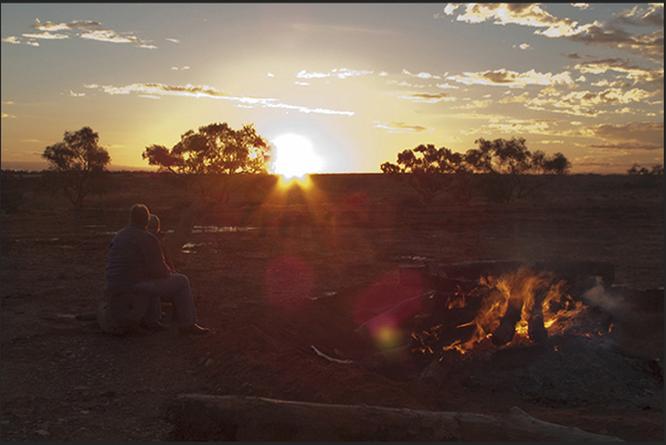 The sun sets on the outback while someone prepare dinner