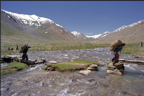 Some nomads crossing the river to bring food to the camp of tents Some nomads crossing the river to bring food to the camp of tents
