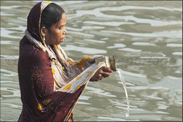 A Pilgrim intent on pouring the Sacred water as a symbolic gesture of recognition and gratitude to the gods